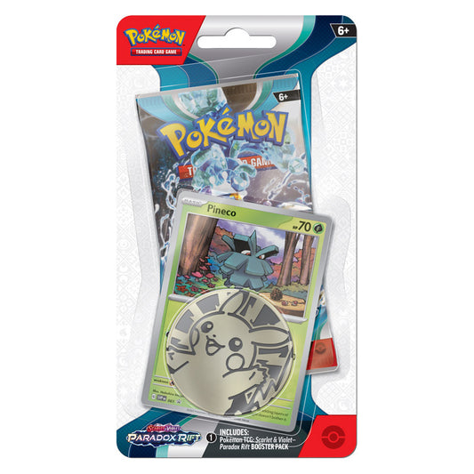 photo of pineco with pikachu coin and booster pack of paradox rift sealed in blister packaging